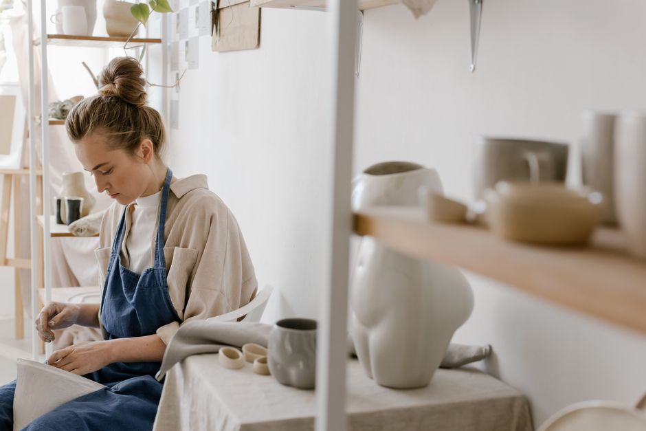 A woman artist carefully crafting pottery in a bright, modern ceramic studio.