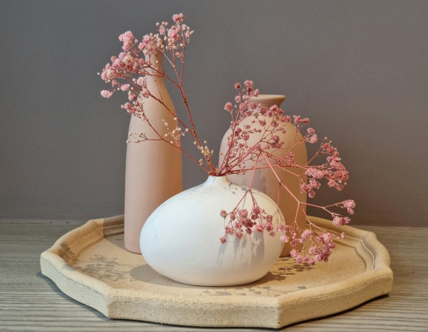 Minimalist decor setup featuring pink gypsophila in ceramic vases on a wooden tray.